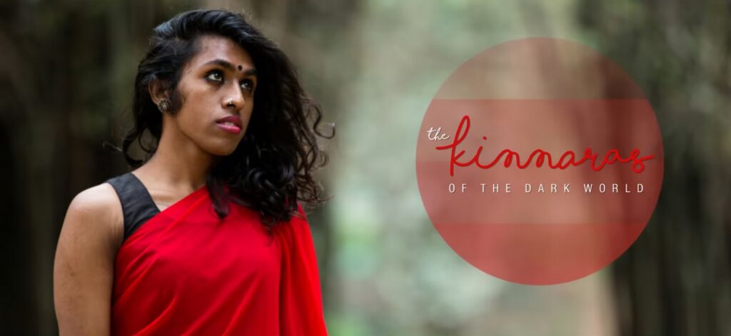 Photo of performer and creator Shilok Mukkati, who is wearing a red sari with a black blouse, her dark and curly hair parted to one side as she gazes off in the distance. The tile of the film, “The Kinnaras of the Dark World”, is superimposed on top of a reddish circle on the photo.