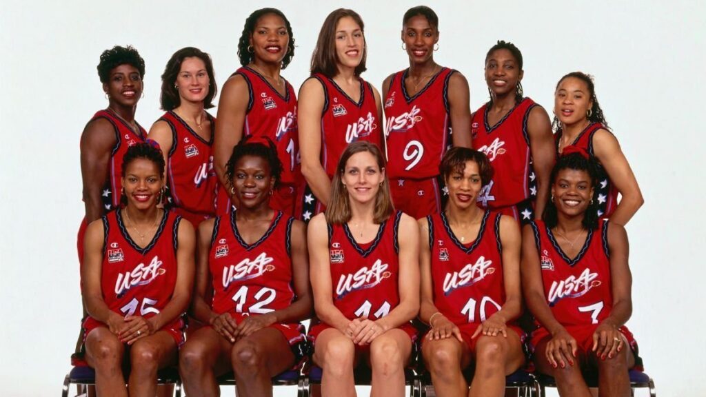 Photo of the roster lined up for a posed photo with the tallest players in the center in the back and the front row seated. They are all wearing red jerseys that say USA.