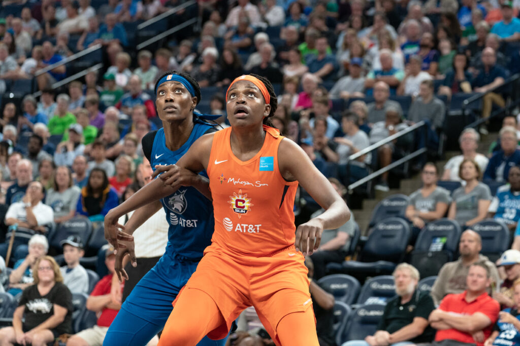 Jonquel Jones crouched in front of Sylvia Fowles as they both look to up to the basket, possibly for a rebound, with a nearly full stadium visible behind them