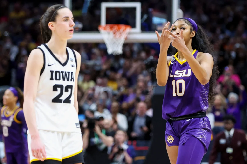 Caitlin Clark standing in her Iowa Hawkeyes jersey, while Angel Reese, in her LSU jersey, is making a gesture with her hands that means “you can’t see me”