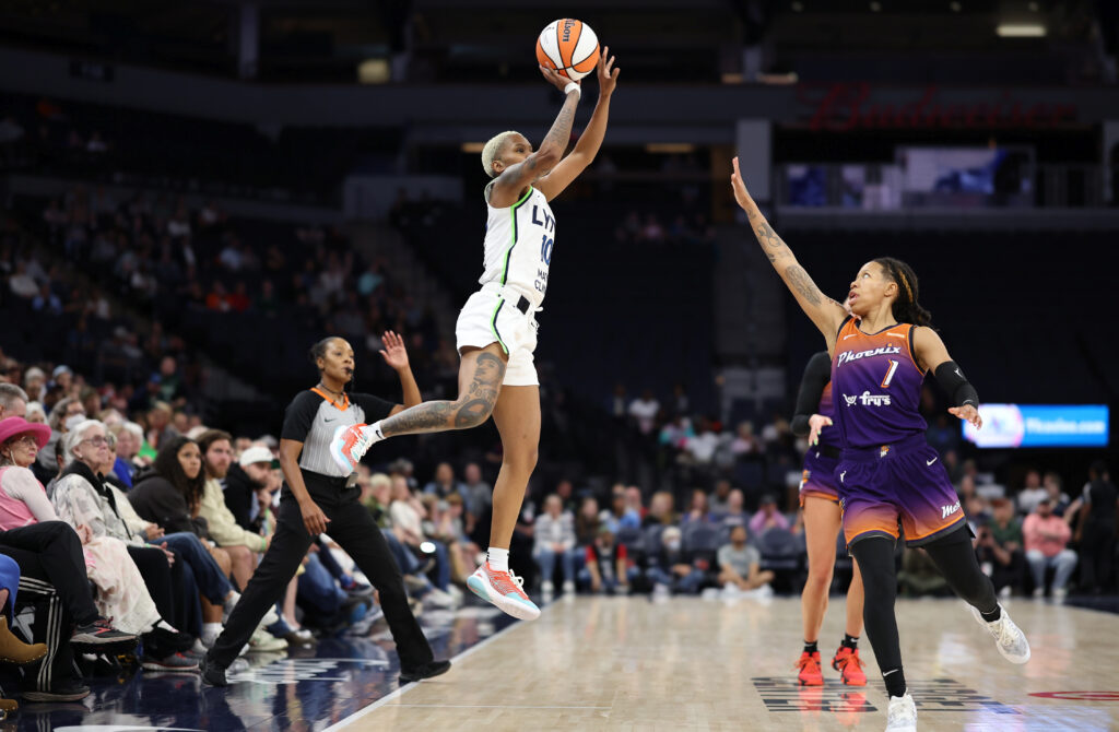 Courtney Williams jumping high off the ground and taking a shot while two Phoenix Mercury defenders try to guard her