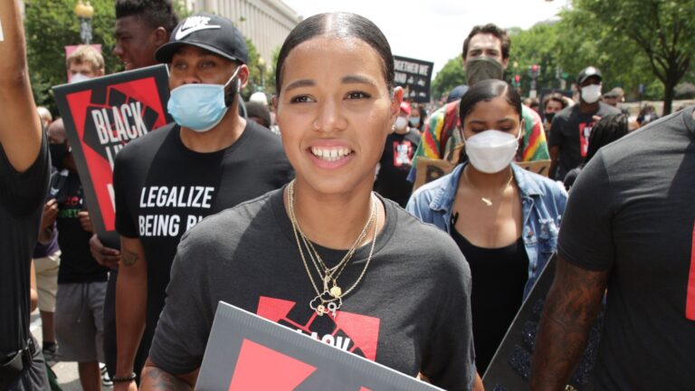 Natasha Cloud is in front of a line of marchers, some wearing masks, carrying signs in support of Black Lives Matter